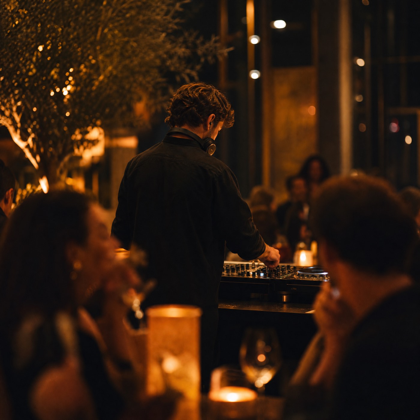 DJ performing behind a booth in an upscale bar lounge
