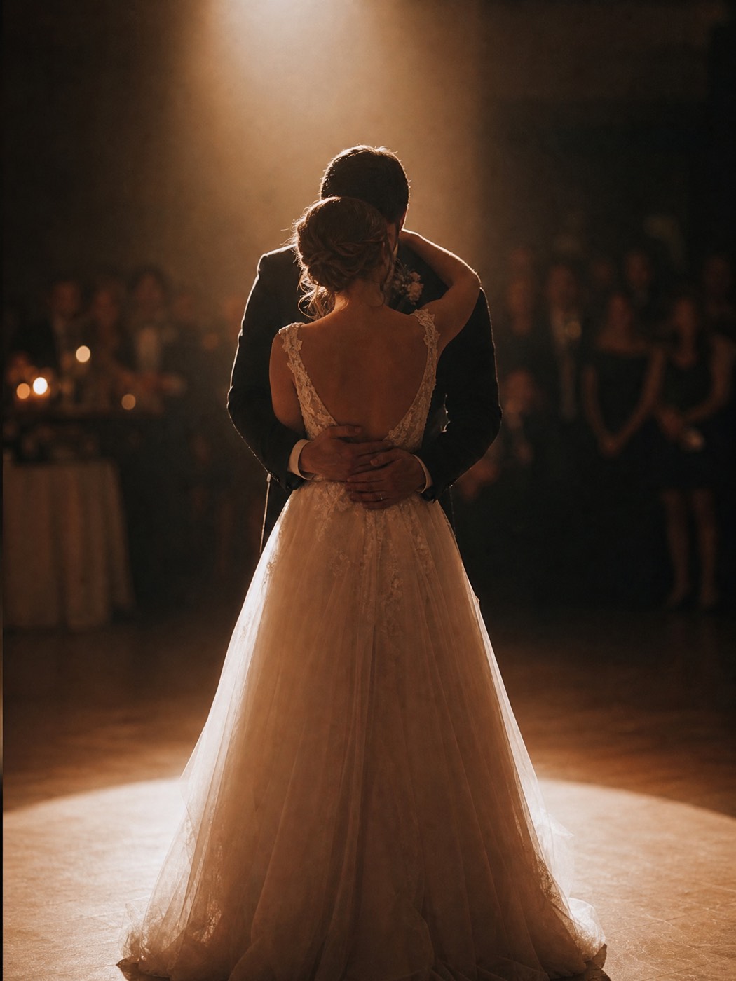 Bride and groom sharing their first dance, softly spotlighted