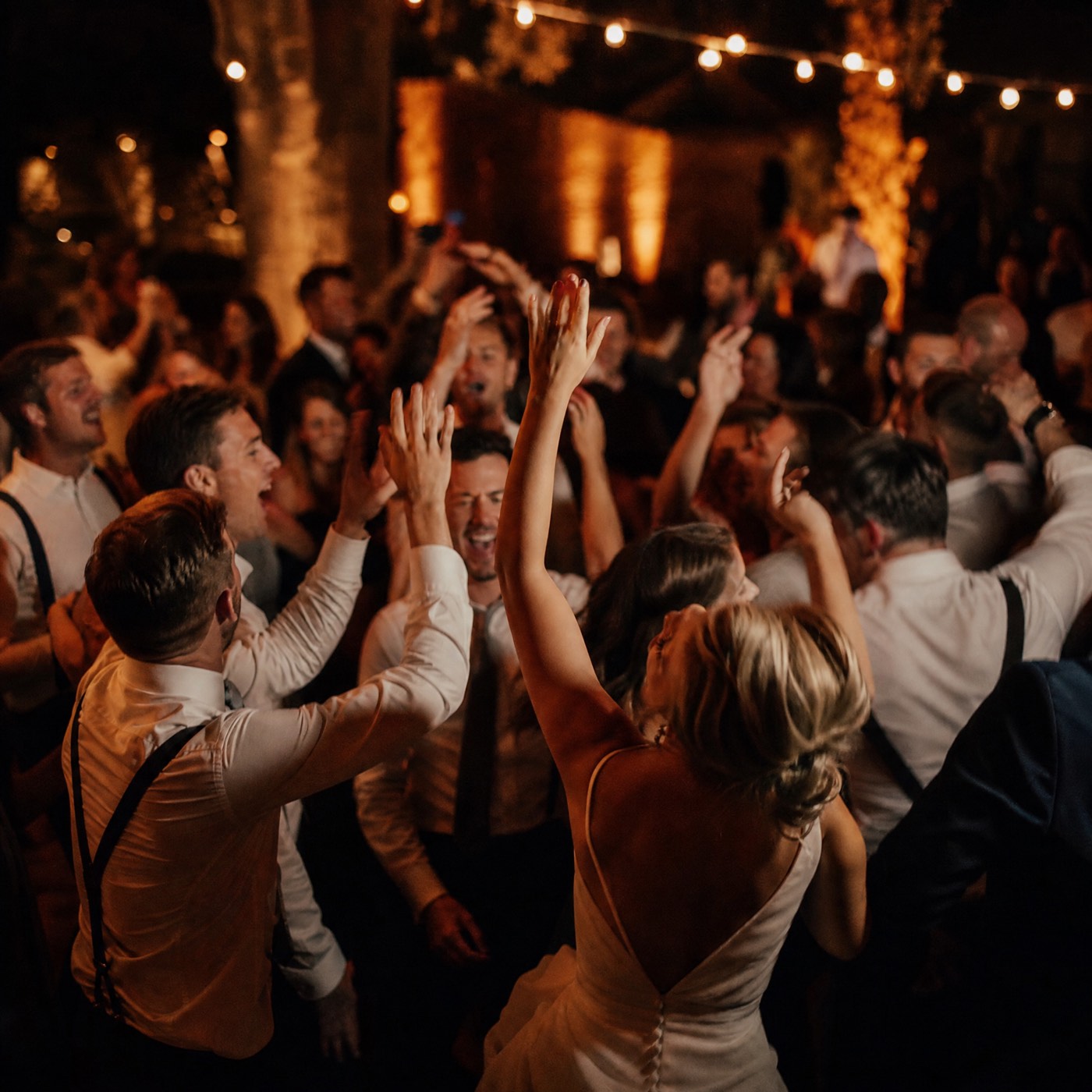 Packed wedding dancefloor at night with guests dancing